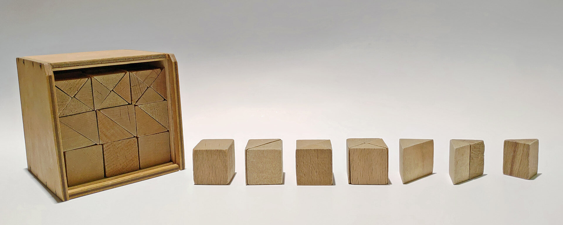 Kuvassa vasemmalla on Fröbelin 5. lahja kokonaisuudessaan. Oikealla puolella on kyseisen lahjan eri muotoja aseteltuna erilaisiin kokoonpanoihin, jotka muodostavat kuution osia.