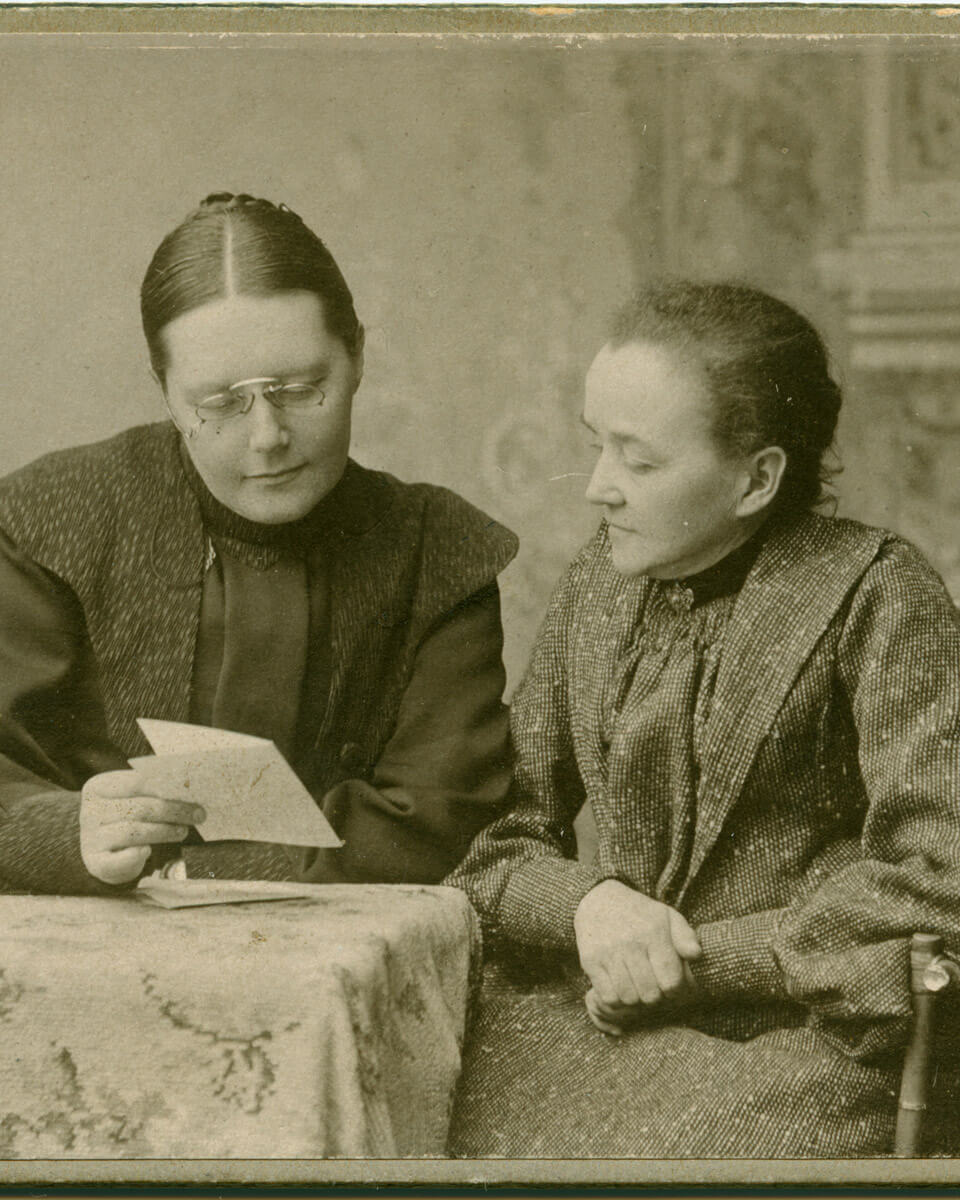 Elisabeth Alander ja Hanna Rothman käyntikorttikuvassa, 1900-1910. Alander pitelee kuvassa kädessään kirjettä, jota he tutkivat yhdessä. Lastentarhamuseon valokuvakokoelma.
