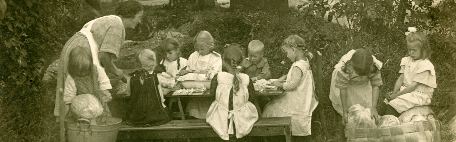 Lapset pilkkomassa kaaleja Kotikallion kesälastentarhan puutarhassa vuonna 1925. Lastentarhamuseon valokuvakokoelma.