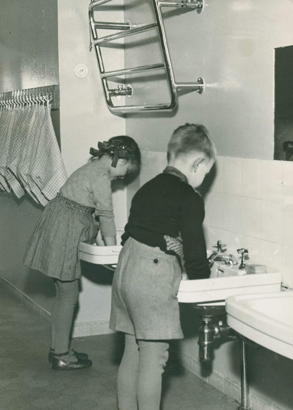 Kaksi lasta pesevät käsiä vierekkäisillä käsienpesualtailla. Altaat on asetettu lapsen ergonomia ja käsienpesukorkeus huomioiden.