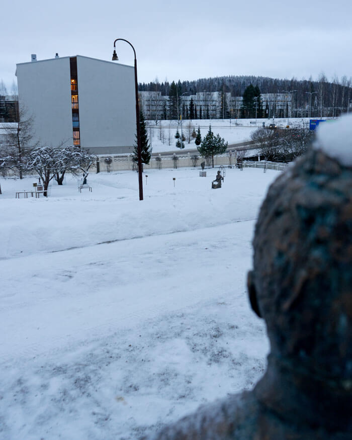 Kuvanveistä Sonja Vectomovin tekemä rintaveistos Hanna Pariviasesta katselle pihan ylitse kohti pronssiveistosta arkkitehti Wivi Lönnistä.
