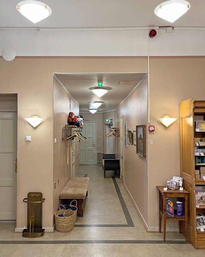 Ennen remonttia aulan seinät olivat pehmeän roosan väriset. Boordiraja oli asetettu lähelle kattoa ja seinän yläosa maalattu katon kanssa valkoiseksi. Roikkuvat kattovalaisimet olivat kartionmalliset. Seinävalaisimet olivat samasta valaisinsarjasta.