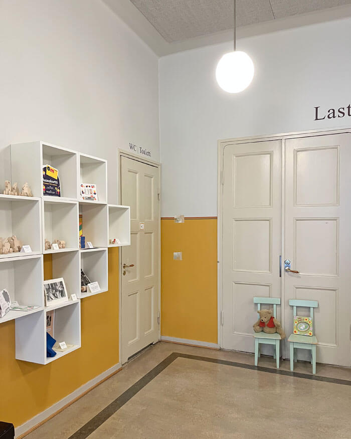 Lähelle wc-tilojen ovea sijoitettiin kuutiolokerikko, joka valkoisena hohtaen raikastaa lämpimän harmaan ja keltaisen seinän yhdistelmää.